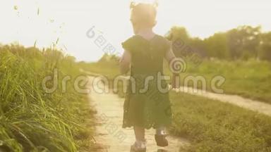 穿着绿色裙子的小女孩走在<strong>阳光</strong>明媚的夏日傍晚的小<strong>路上</strong>